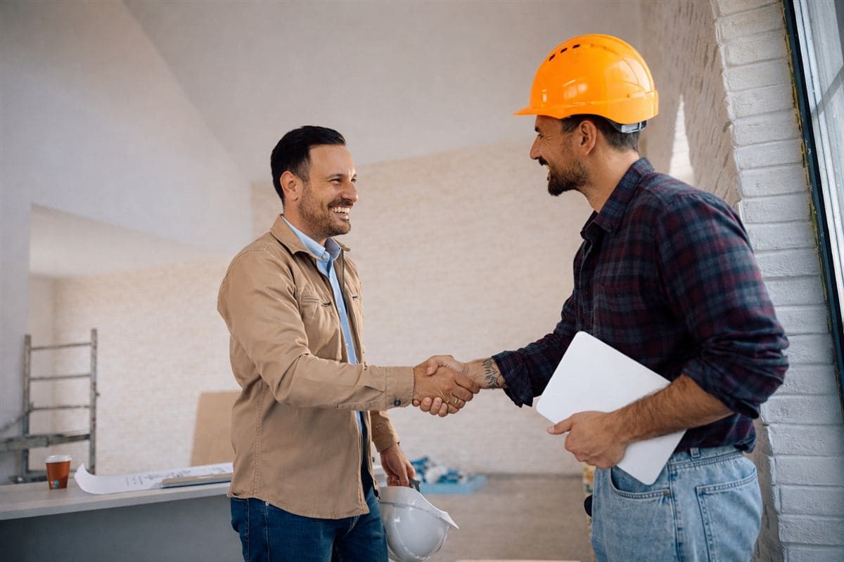 A contractor and client shaking hands on a job site